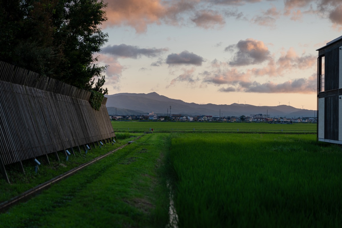 竹垣越しに続くあぜ道と夕景の山並み(鶴岡)