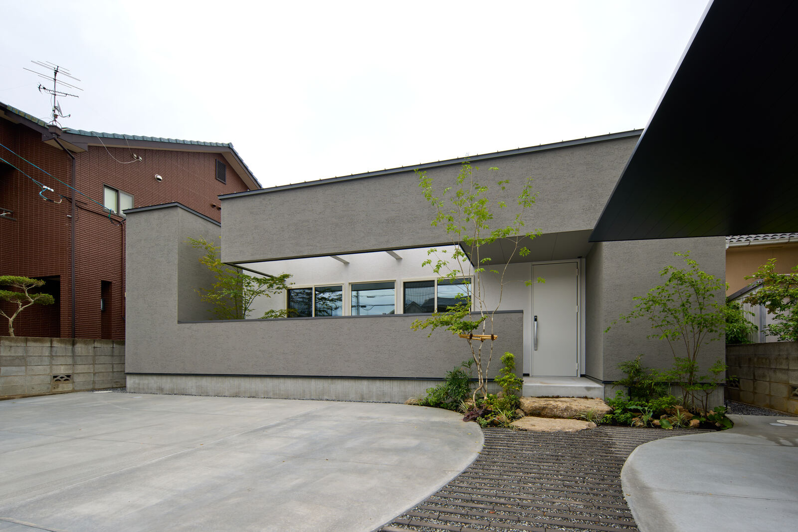 隣家に挟まれた敷地に建つ低い家