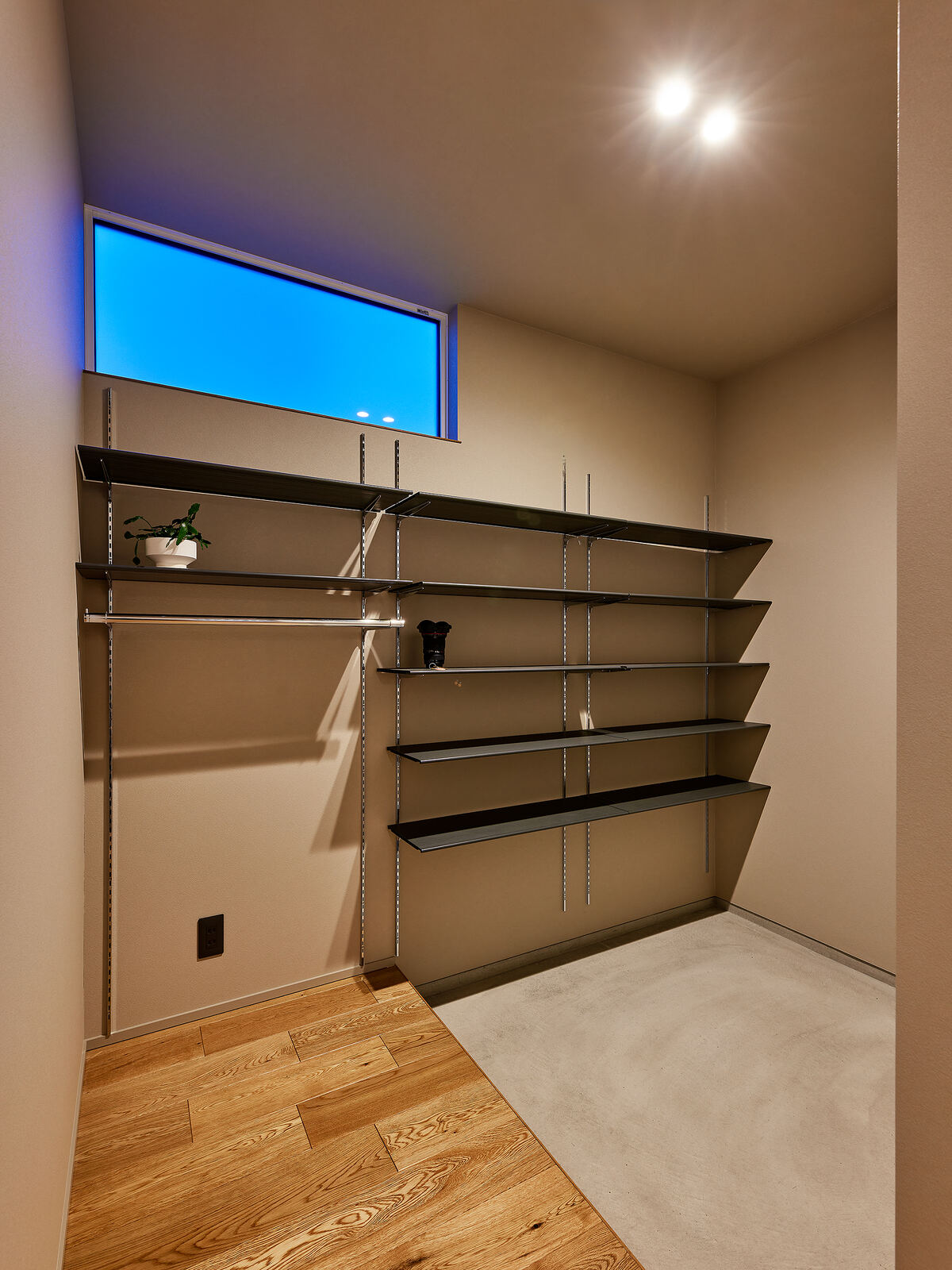 高窓のある部屋に物干しの棚が並ぶランドリールーム