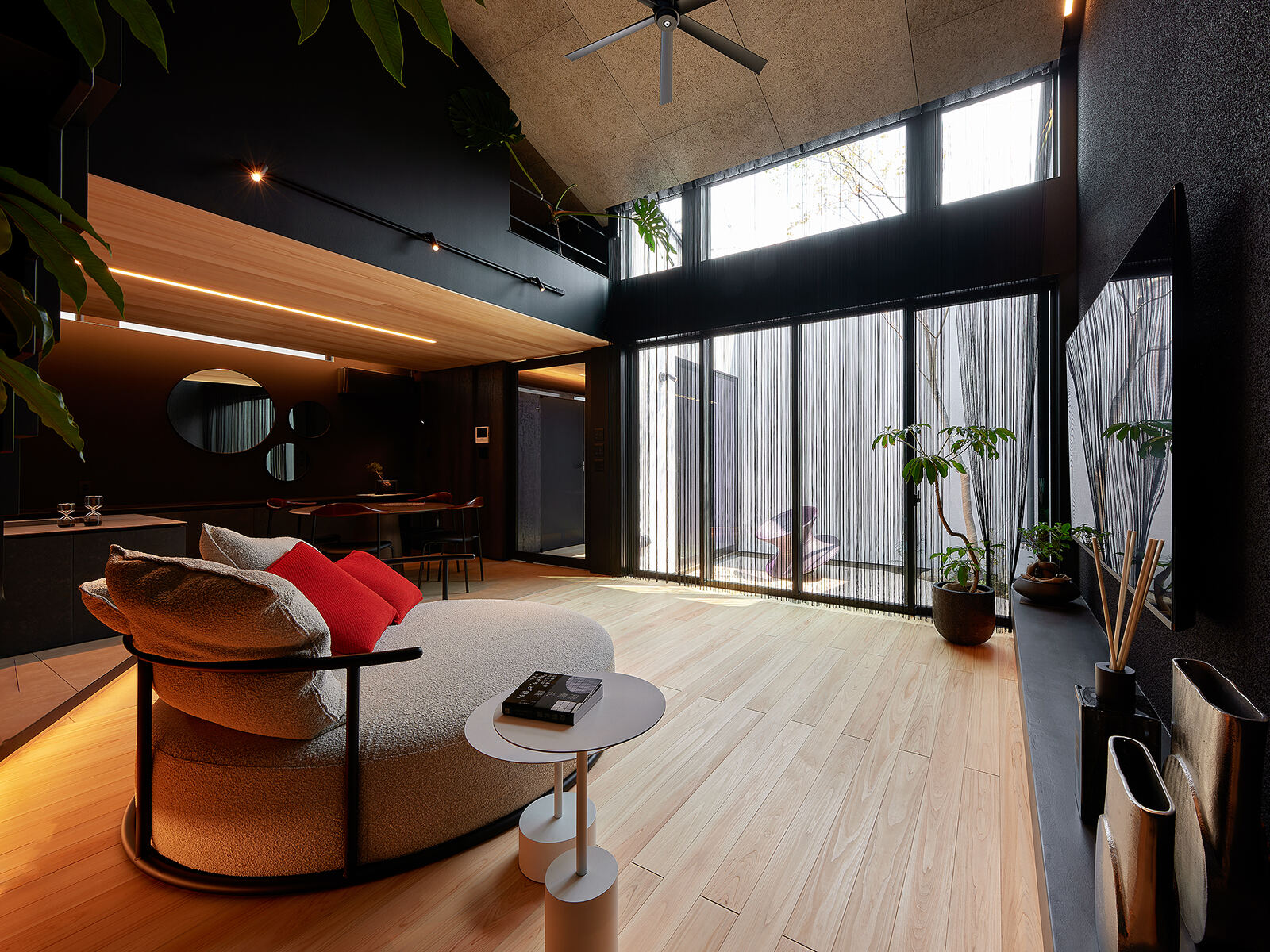 黒い天井のリビング。大きな窓の外に緑