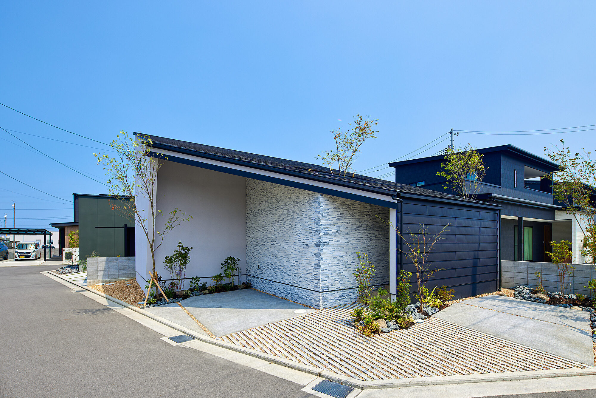 晴れた日の、黒い板張りと石張りの平屋モデルハウス外観