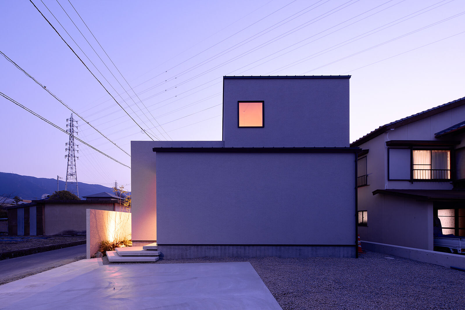 夕暮れ、窓のあかりがともる二世帯住宅