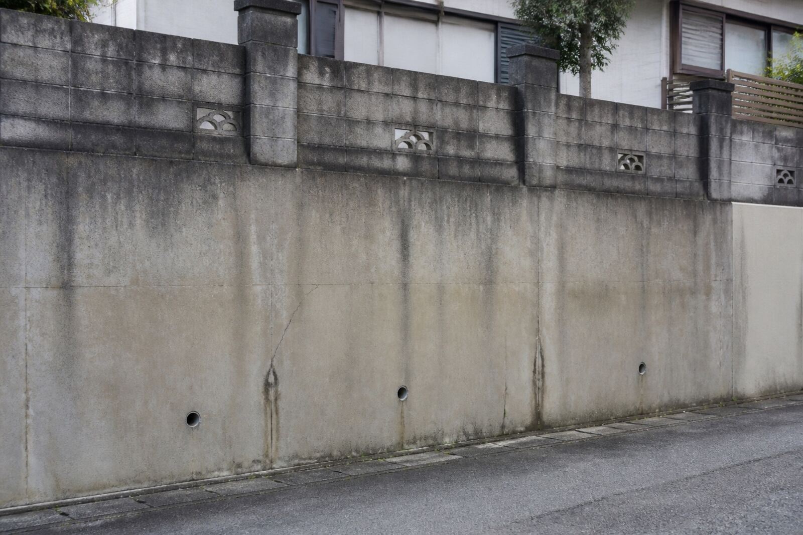 道路との境にある古い擁壁と、水抜き穴のまわりの汚れ
