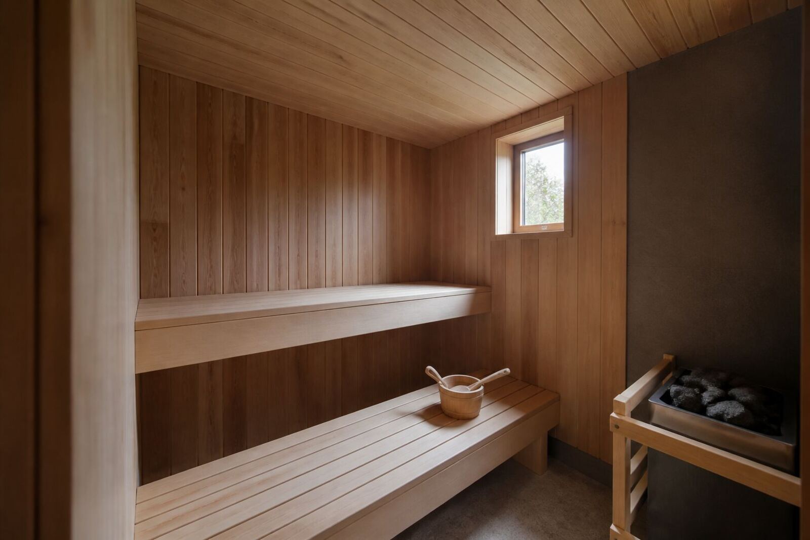 木のベンチとヒーターのある屋内のプライベートサウナ室
