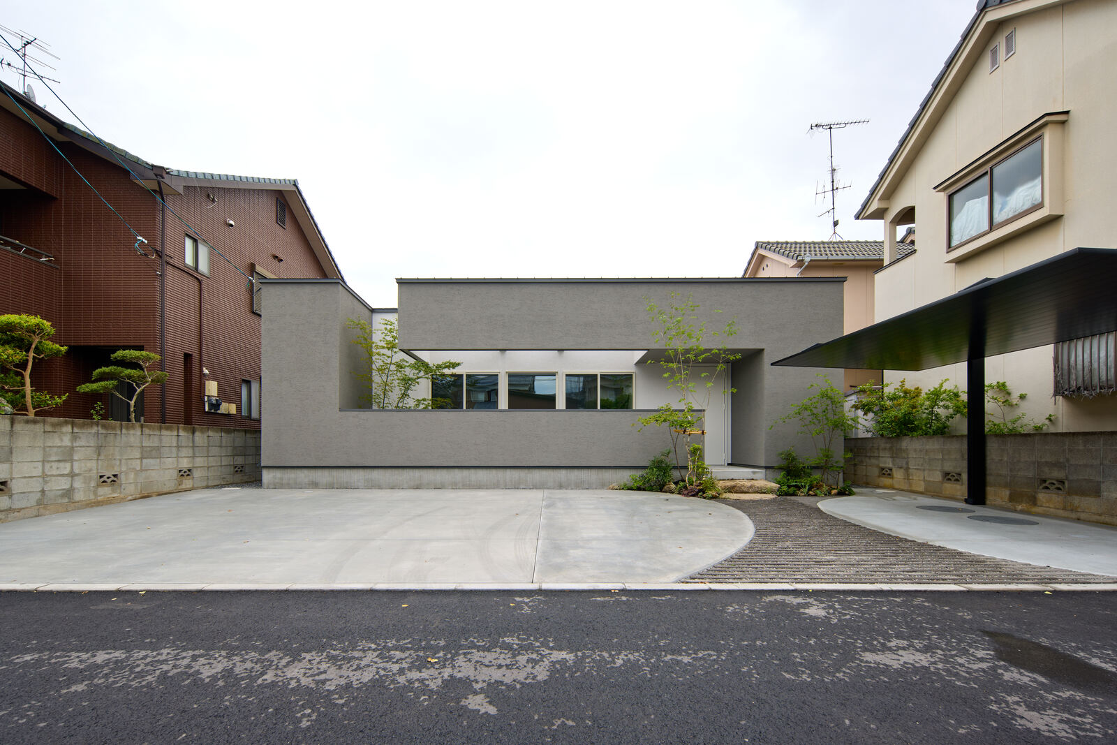 既存の住宅に挟まれた敷地に建つ、低く水平な住宅