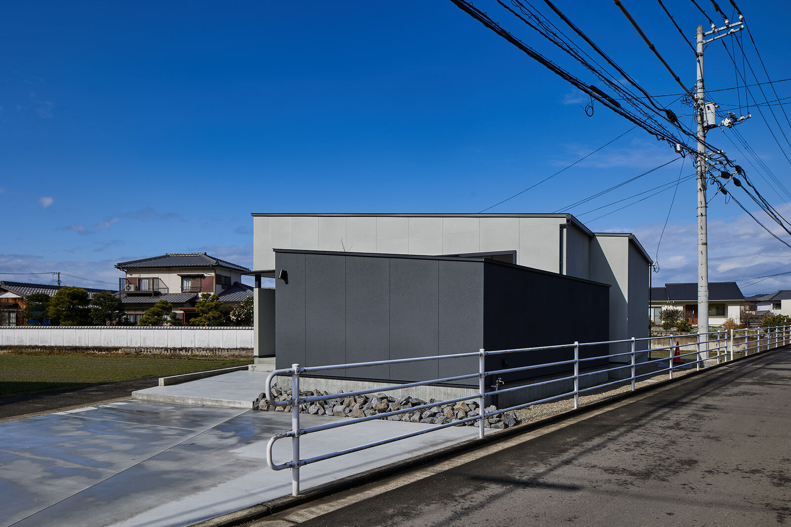 前面道路の広い角地に建つ、黒くて低い住宅