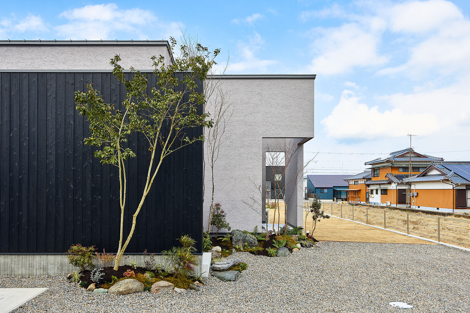 黒い外壁と庭木、岩の植栽
